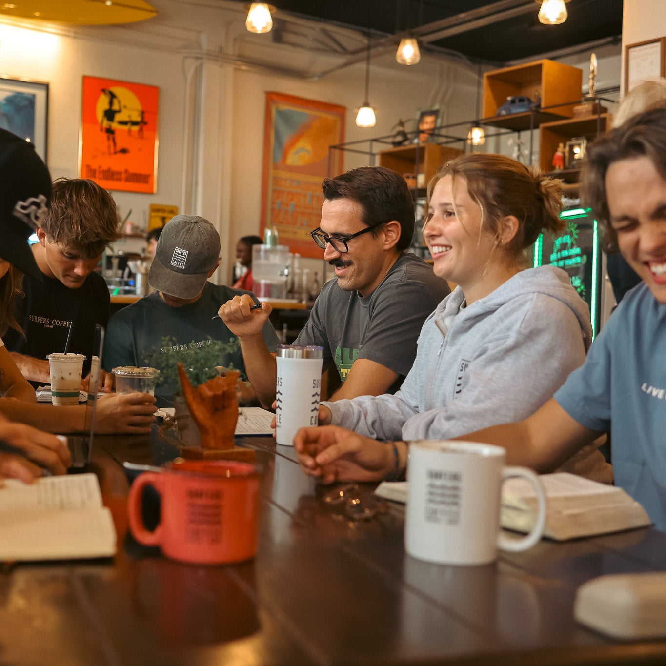 Group of people sitting around a table in a casual setting, possibly a cafe or restaurant.