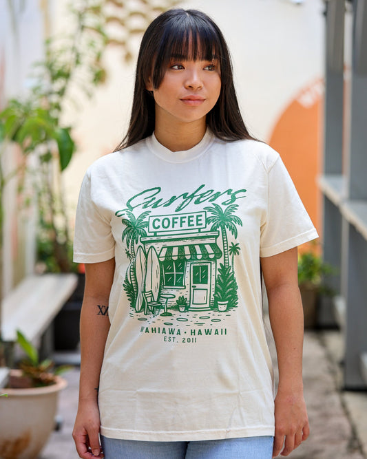 Person wearing a white t-shirt with green graphics and text outdoors.