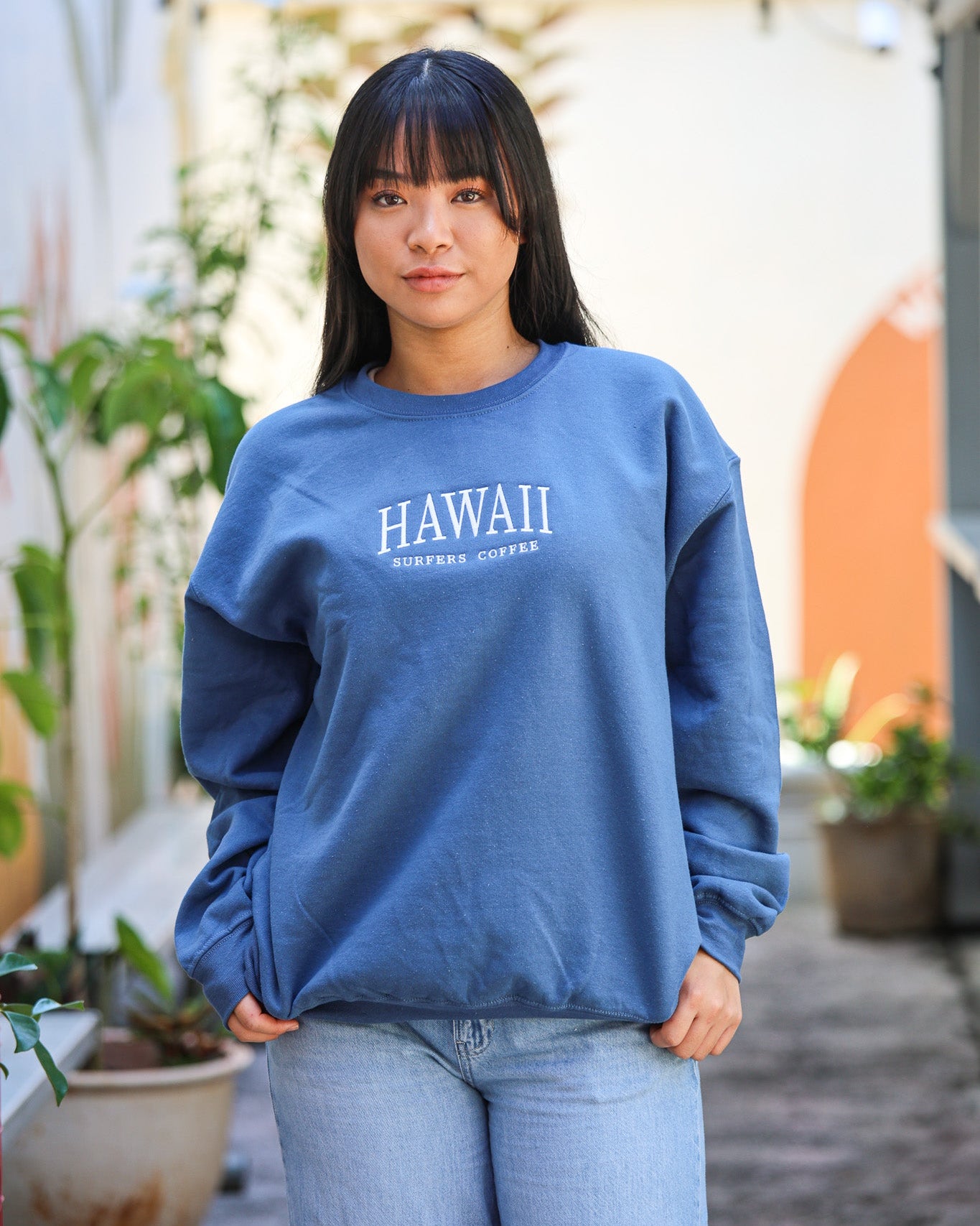 Person wearing a blue sweatshirt with 'HAWAII' text, standing outdoors.