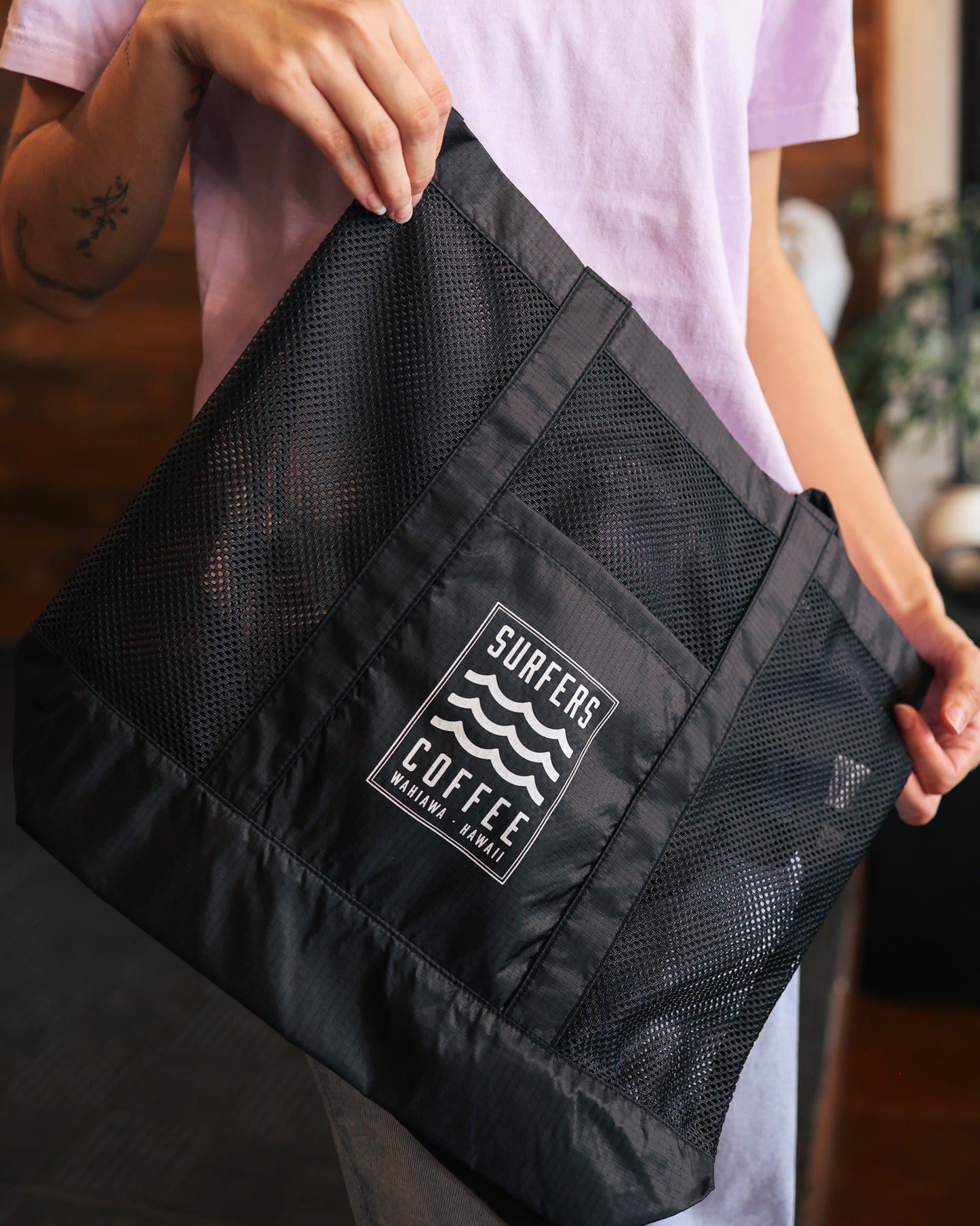 Person holding a black bag with 'Surfers Coffee' logo