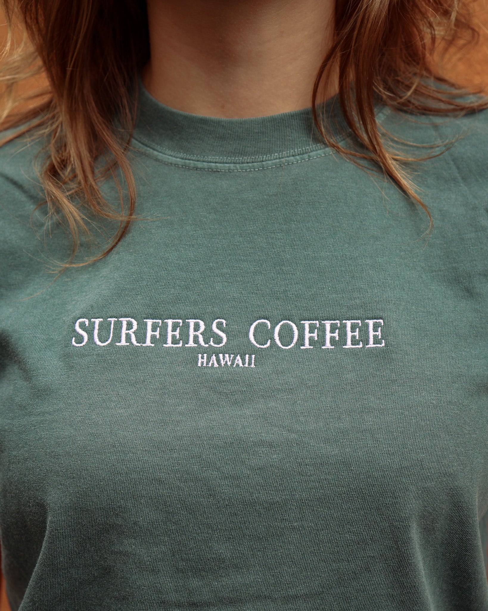 Green t-shirt with 'Surfers Coffee Hawaii' text on a person wearing it.